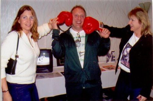 A man holding up a boxing glove with two women and another woman.