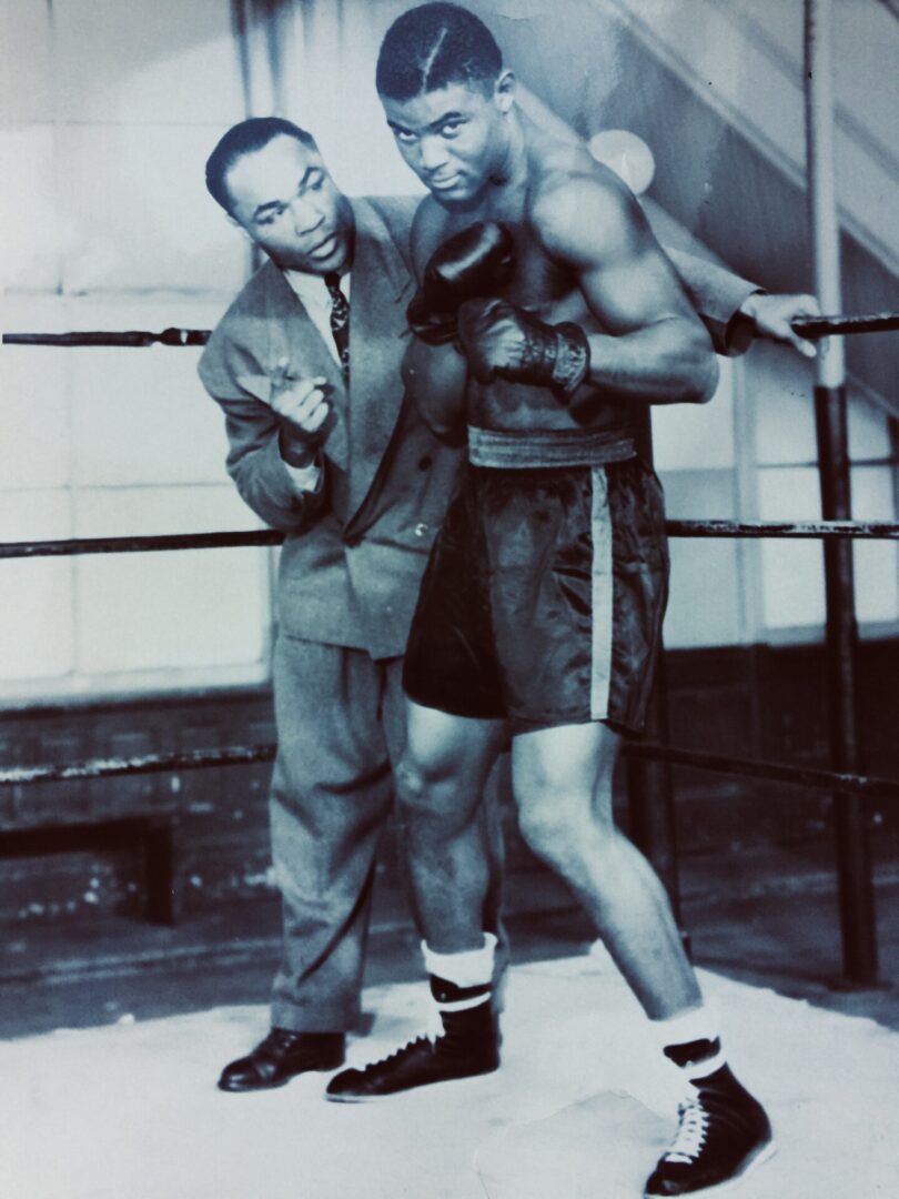 A man and a woman posing for the camera in boxing gear.