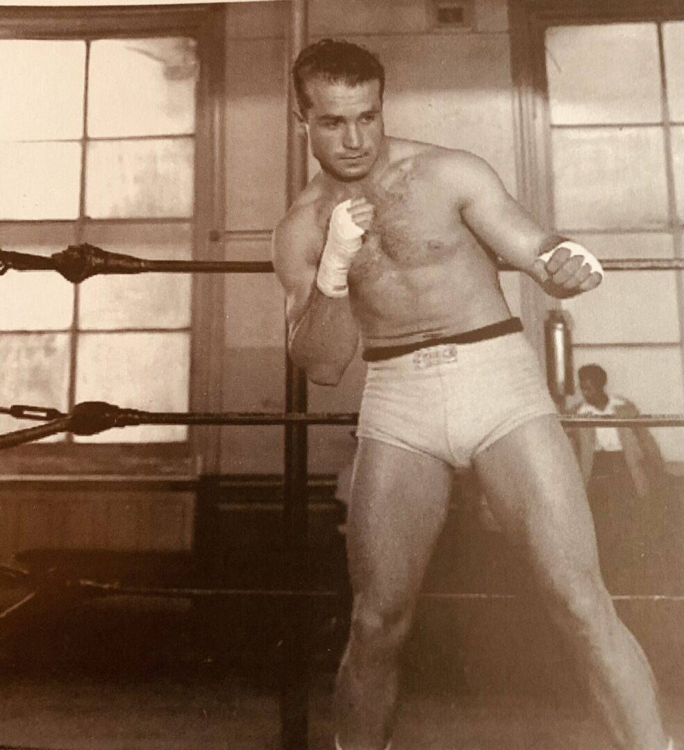 A man in white trunks is standing in the ring.